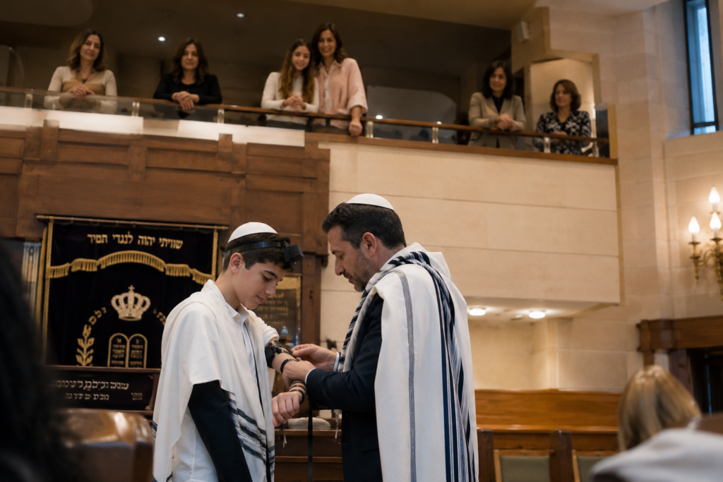père posant les téfilines à son fils à la synagogue